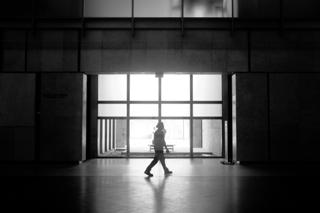 A man in silhouette framed by ceiling-high glass windows in a museum.