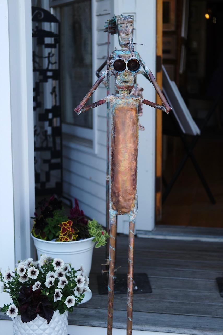 Metal sculpture of a figure holding up binoculars.