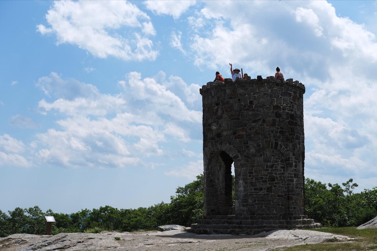 Woman and a girl waving from atop a stone tower.