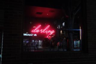 A pink neon sign in script saying “darling”.