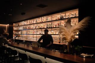 Bartender backlit by shelves of liquor.