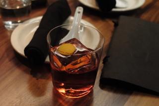 A whiskey tumbler containing a big block of ice with a slice of yellow fruit balanced on top.