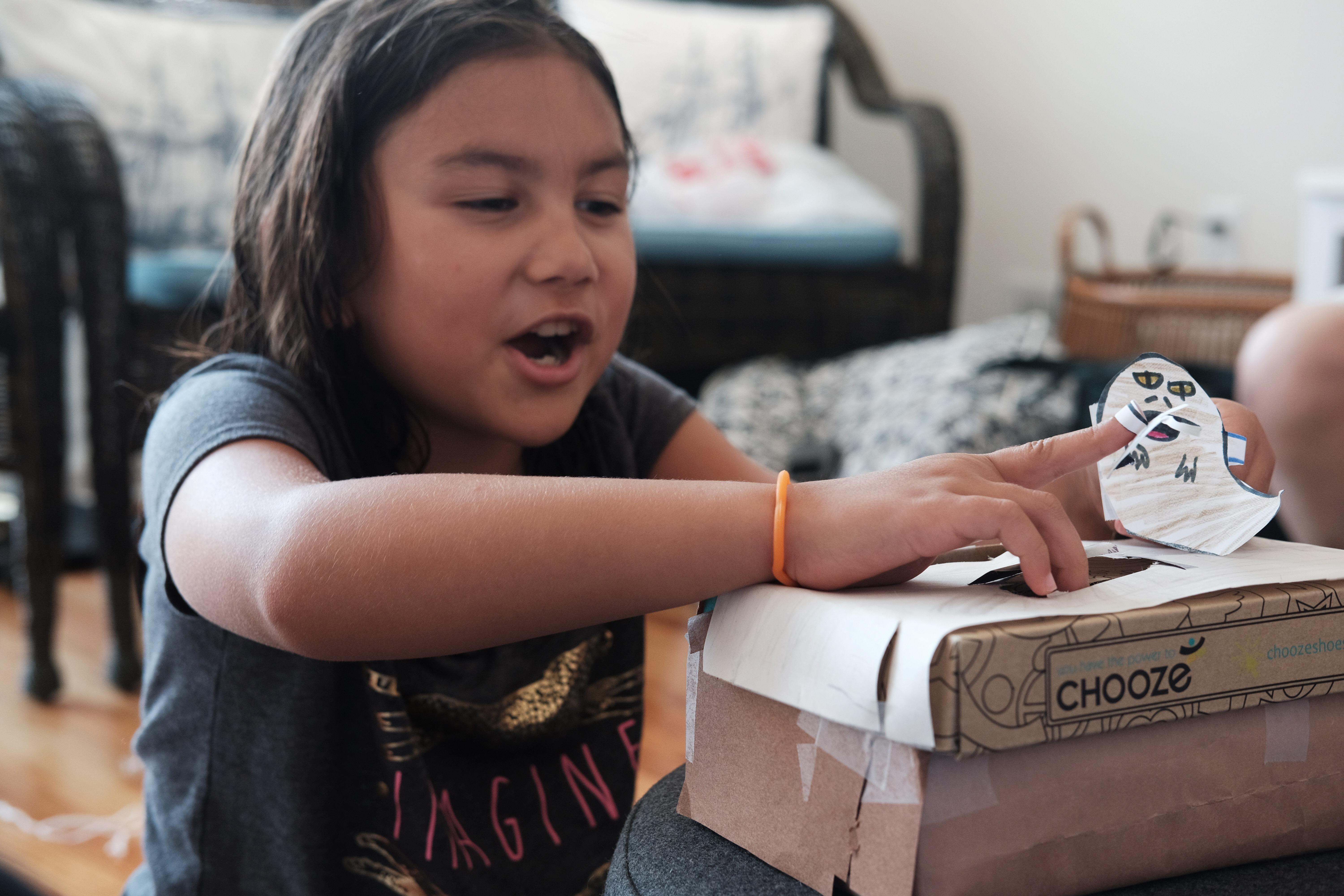 A young girl acts out a scene from Return of the Jedi using paper puppets.