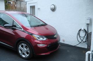 A red hatchback plugged into a level 2 EV charger.