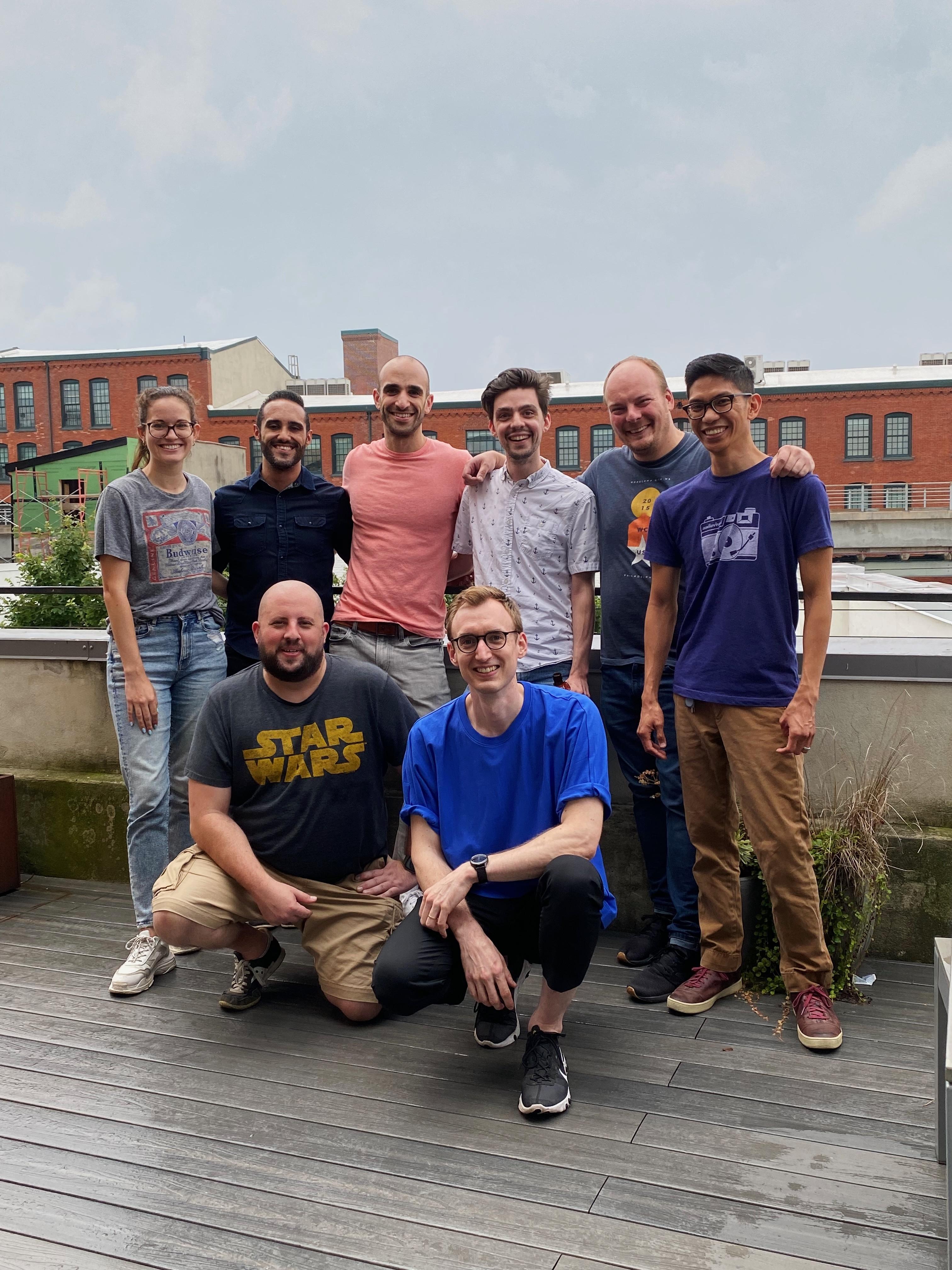 A small group of men and women pose in an outdoor deck.