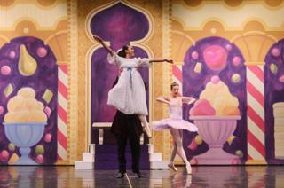 A young dancer being lifted above the stage.