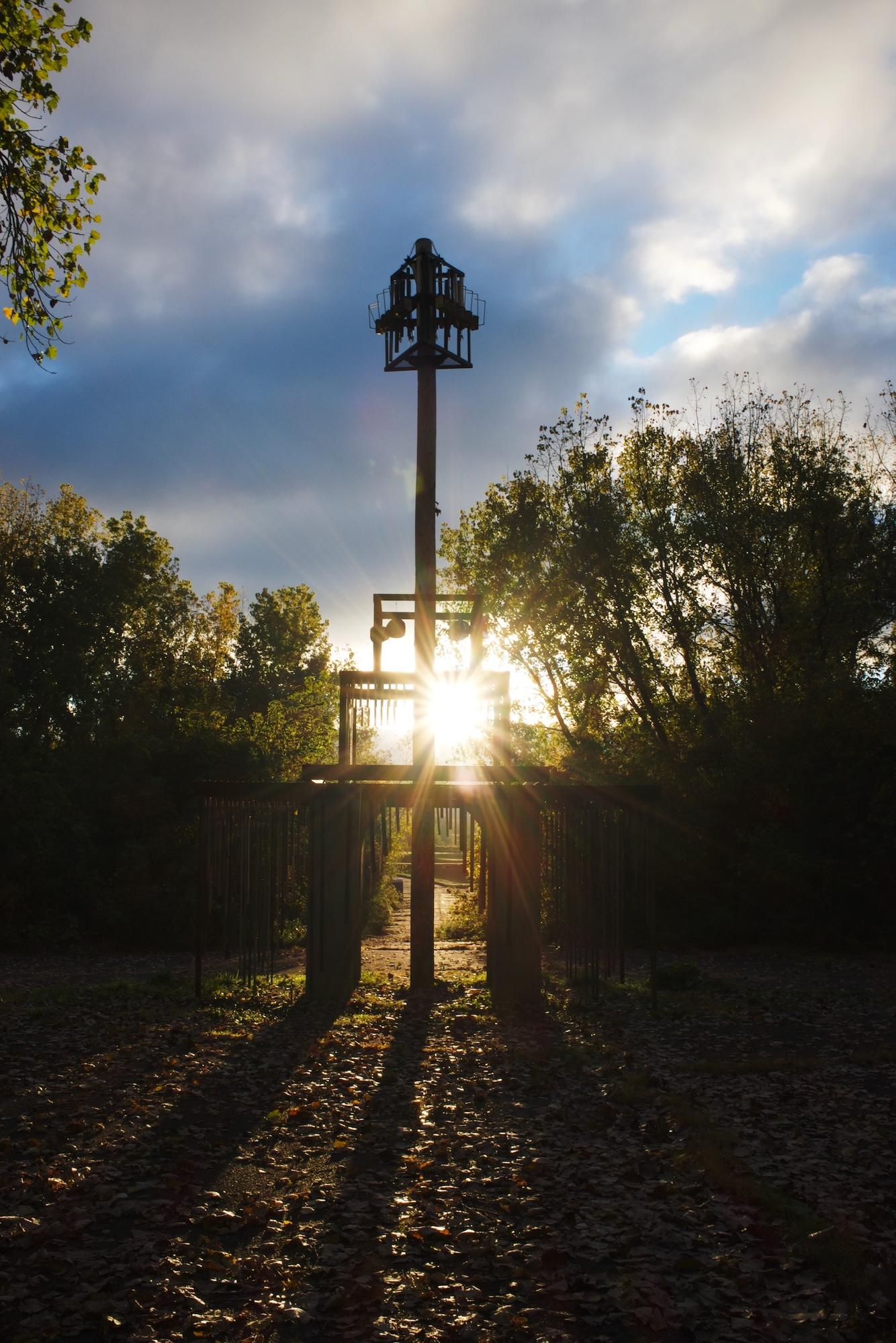 Sunrise flaring through a concrete and metal sculpture.