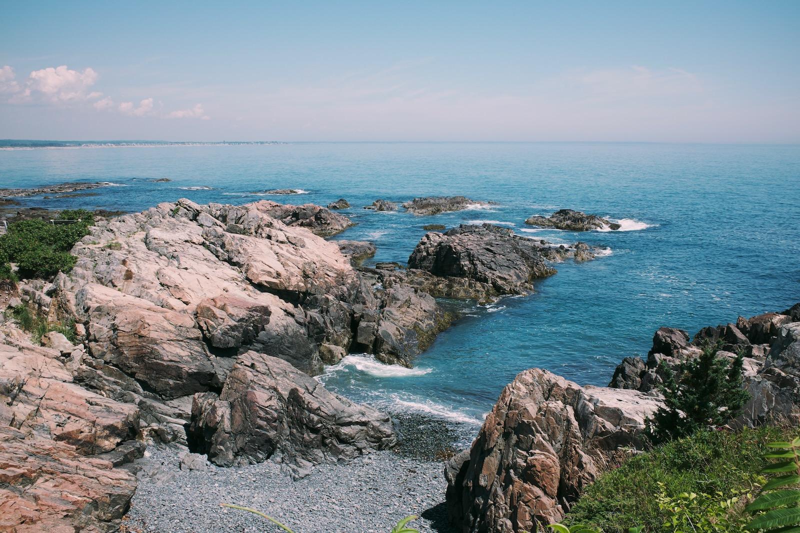 Rocky coastline extending out into the water, with a hazy horizon in the background.