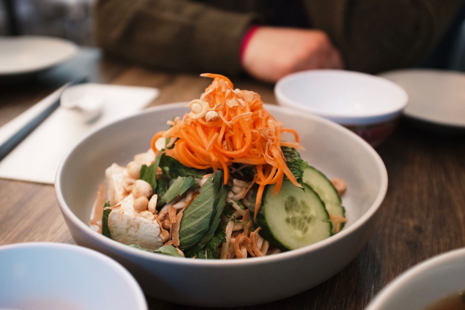 A tofu bowl topped with artfully shredded carrots and peanuts.