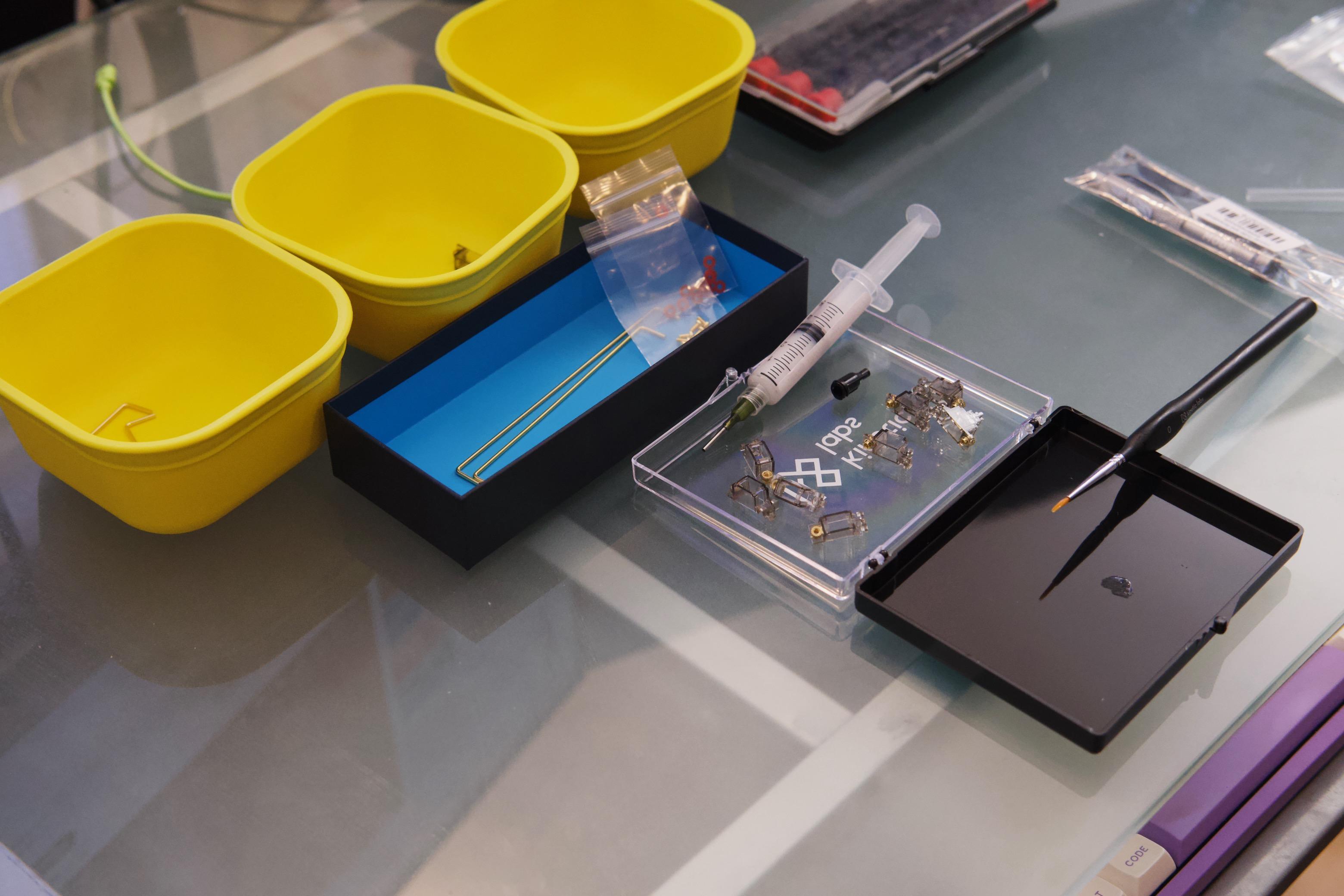 Disassembled keyboard stabilizers and a syringe full of lubricant, awaiting assembly.