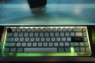 Keyboard lit with LED underglow in a green/yellow hue.