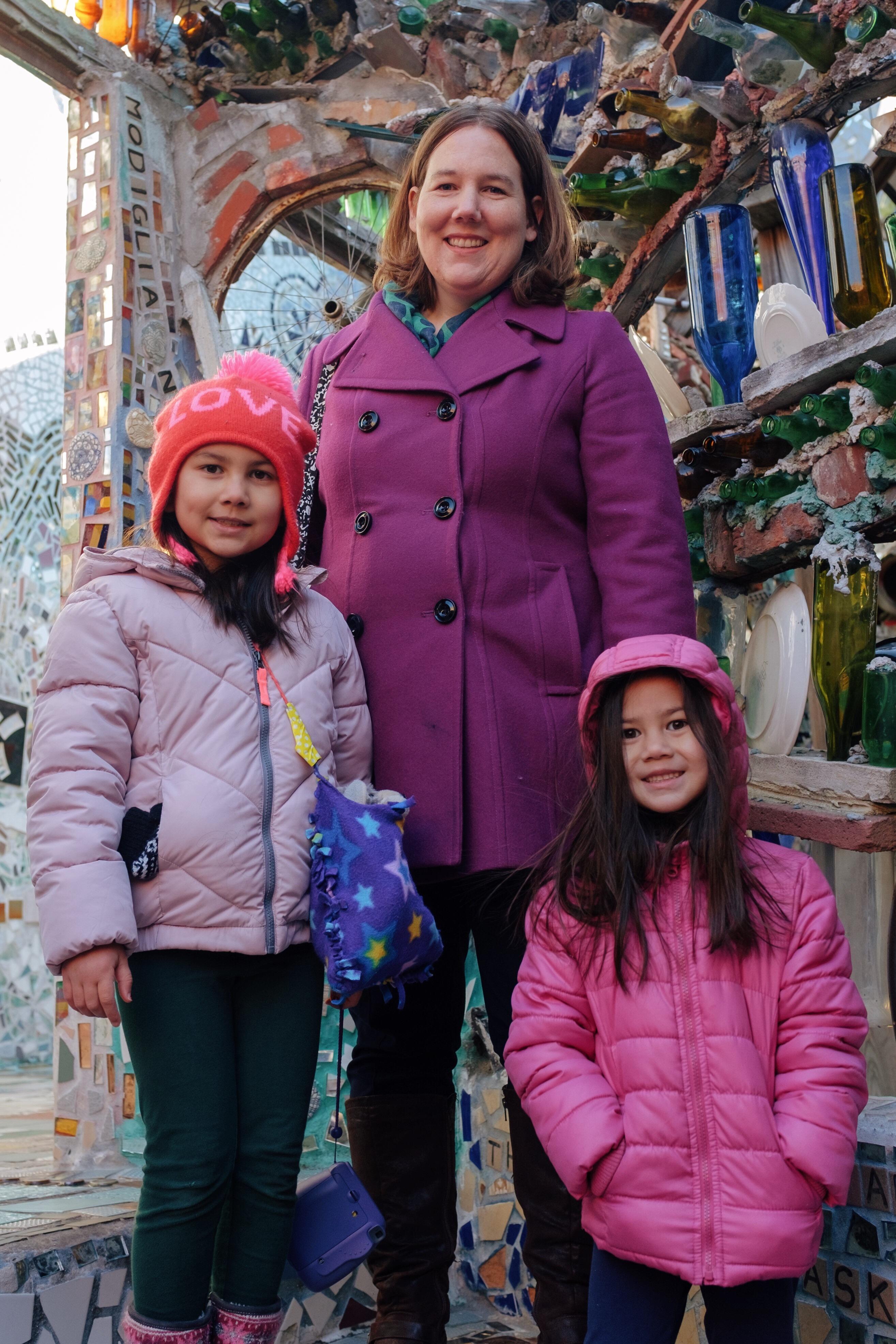 Woman and two girls stand on a stairway, framed by sculpture.