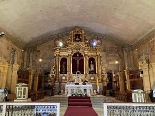 Interior of a church, with the statues housed in an altar decorated in gold.