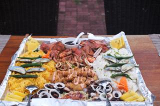A boodle fight spread with shrimp, crabs, barbecued chicken, and fried rice