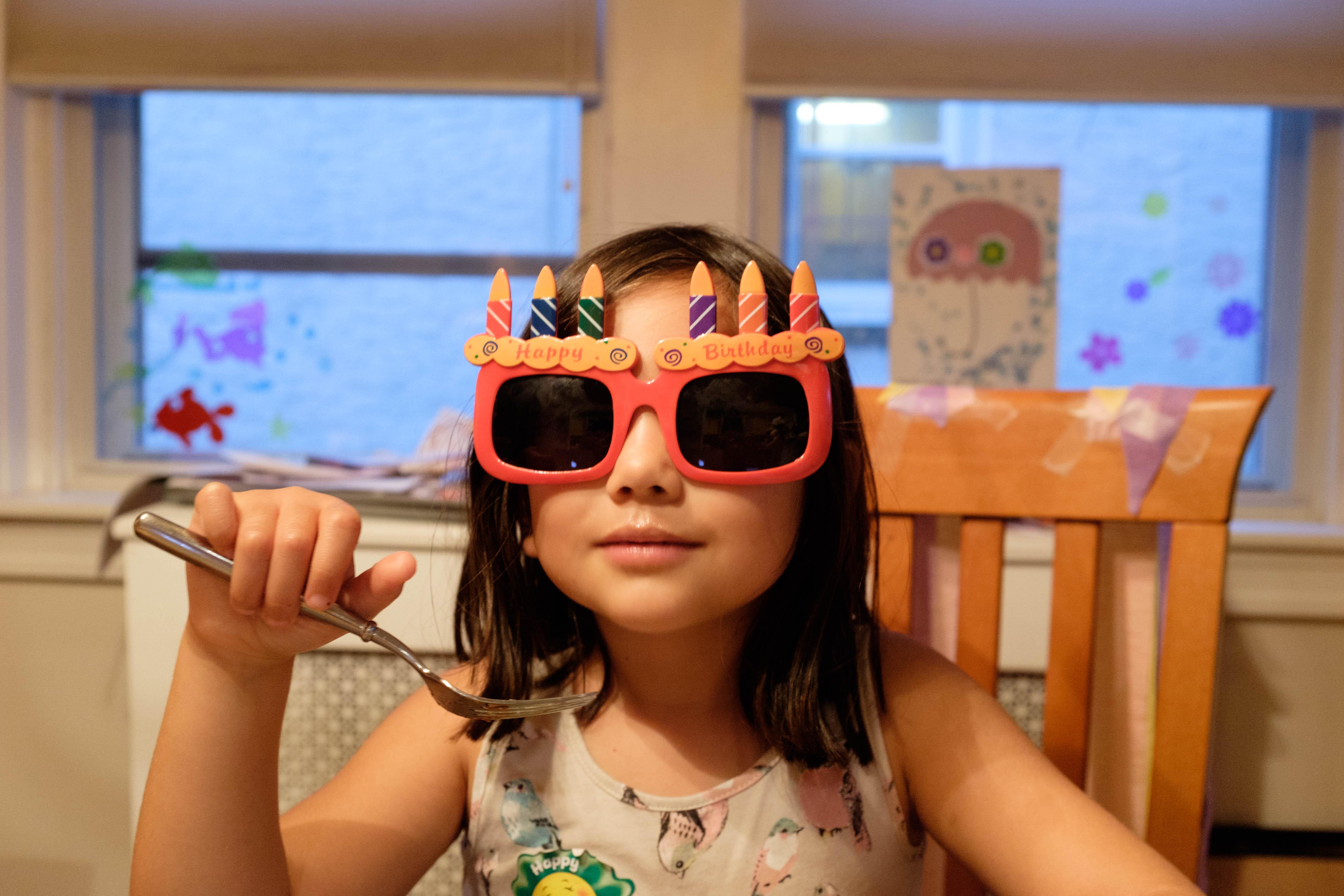 Girl wearing birthday candle sunglasses.