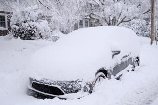 Minivan almost entirely covered in snow.