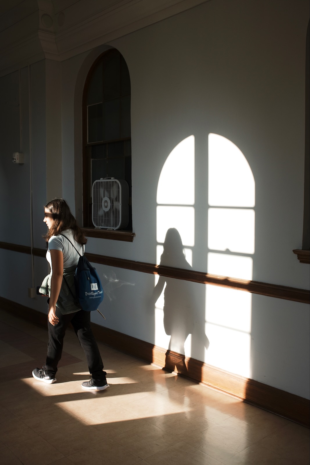 A young woman is framed in the shadow of a hallway window at Vassar College’s Main building.