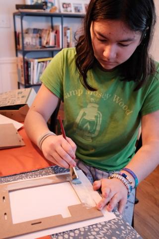 A young woman paints the floor of a model.