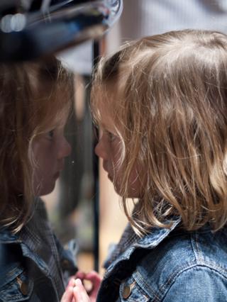 A young boy reflected in an oven door.