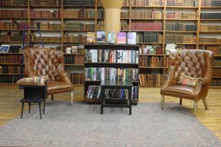 Two leather chairs in a room lined with books from floor to ceiling.