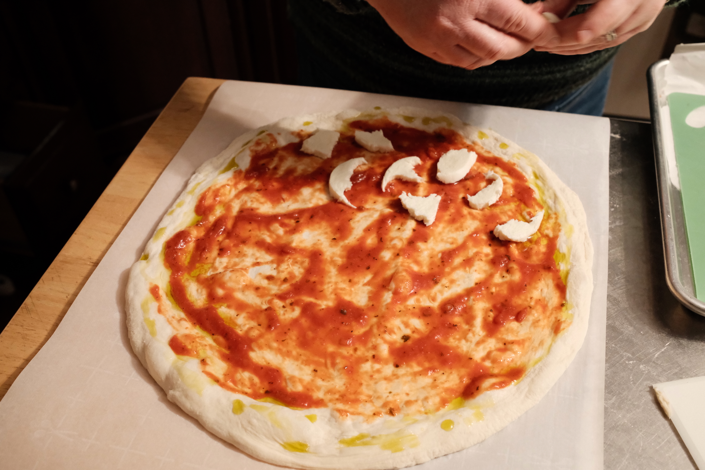 Fresh mozzarella being pulled by hand and sprinkled.