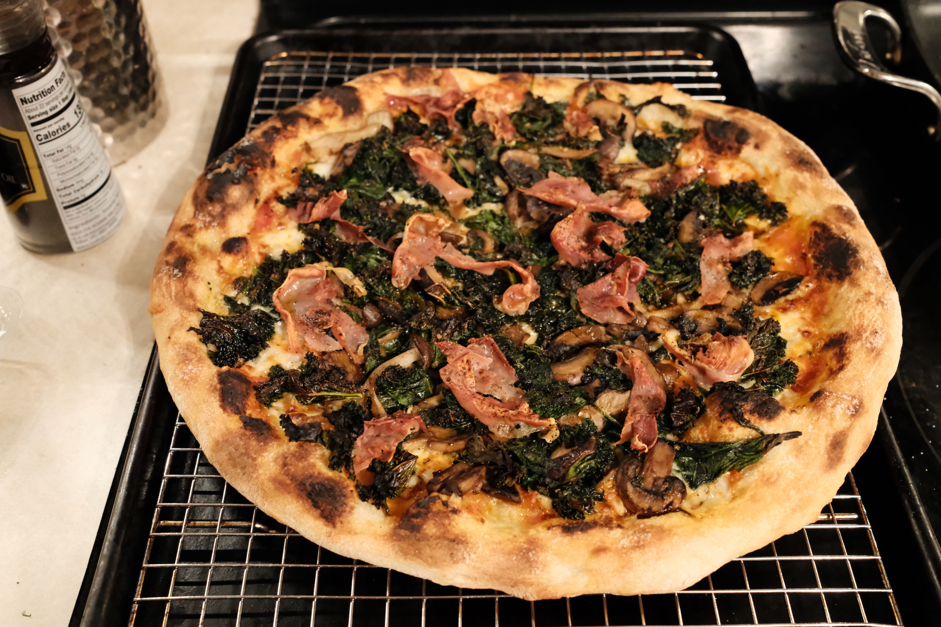 A pizza fresh from the oven, cooling atop a wire rack.